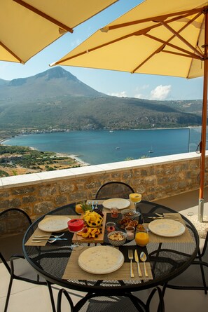 Mesa lista para el desayuno con vista a la montaña y al mar.