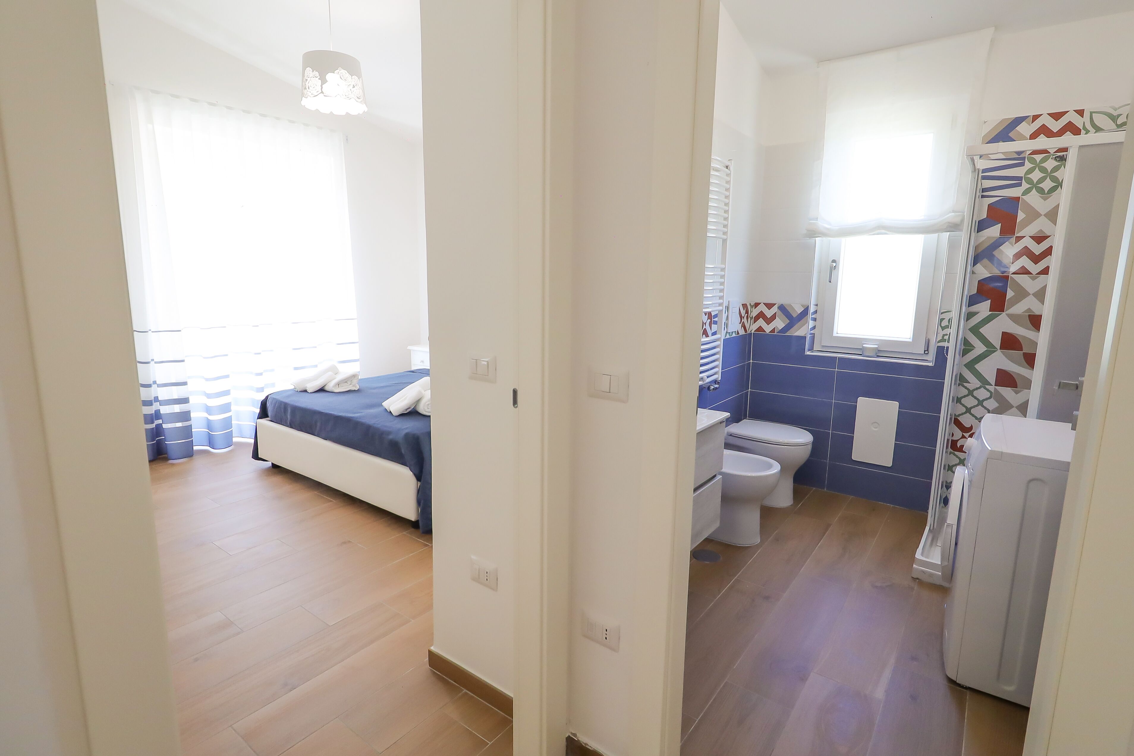 A hotel room with a bed, a bathroom with a toilet and sink, and a shower area.