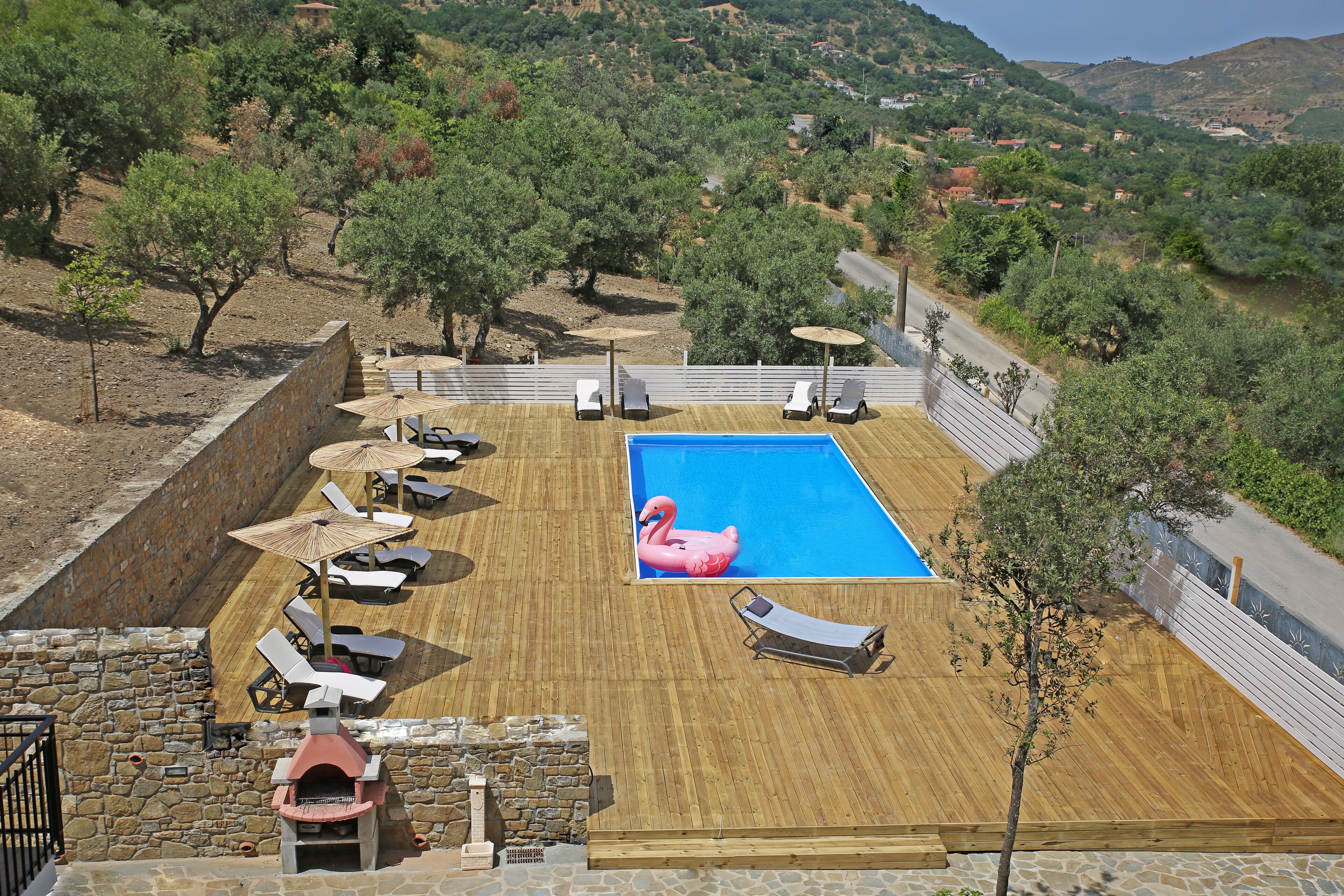 Une terrasse en bois avec une piscine, des chaises longues et un flotteur en forme de flamant rose.