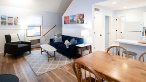 A compact living space with a dining area, a sofa, a chair, and a lamp. - Goshorn Lake Resort Cottage #17 (Saugatuck)