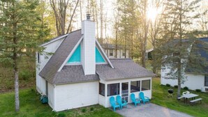 A white house with a grey roof and a blue chimney, surrounded by trees. - Goshorn Lake Resort Cottage #17 (Saugatuck)