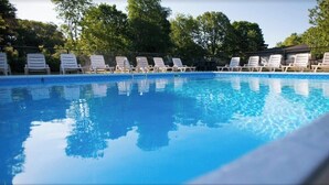 A swimming pool with white lounge chairs arranged around it, surrounded by trees. - Goshorn Lake Resort Cottage #2 (Saugatuck)