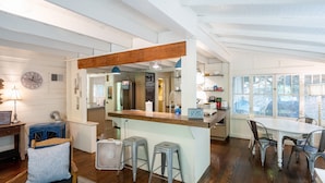 Una cocina moderna con una isla de madera, taburetes de bar y una zona de comedor con sillas de metal.