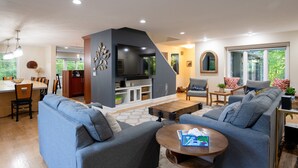 A modern living room with a fireplace, sofas, a dining area, and a kitchen.