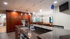 A modern kitchen with wooden cabinets, a granite countertop, and pendant lighting.