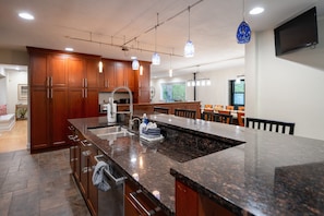 A modern kitchen with wooden cabinets, a granite countertop, and pendant lighting.