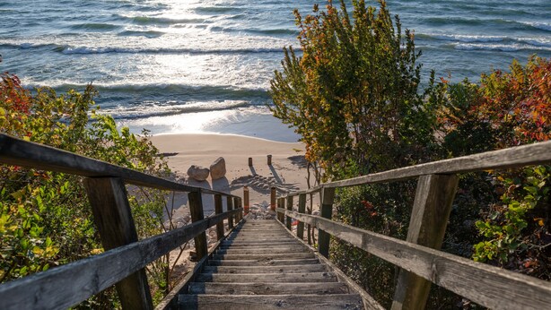 A wooden staircase leading to a beach with ocean views. - Lakefront Cottage | Private Beach + Sunset Views (Holland)