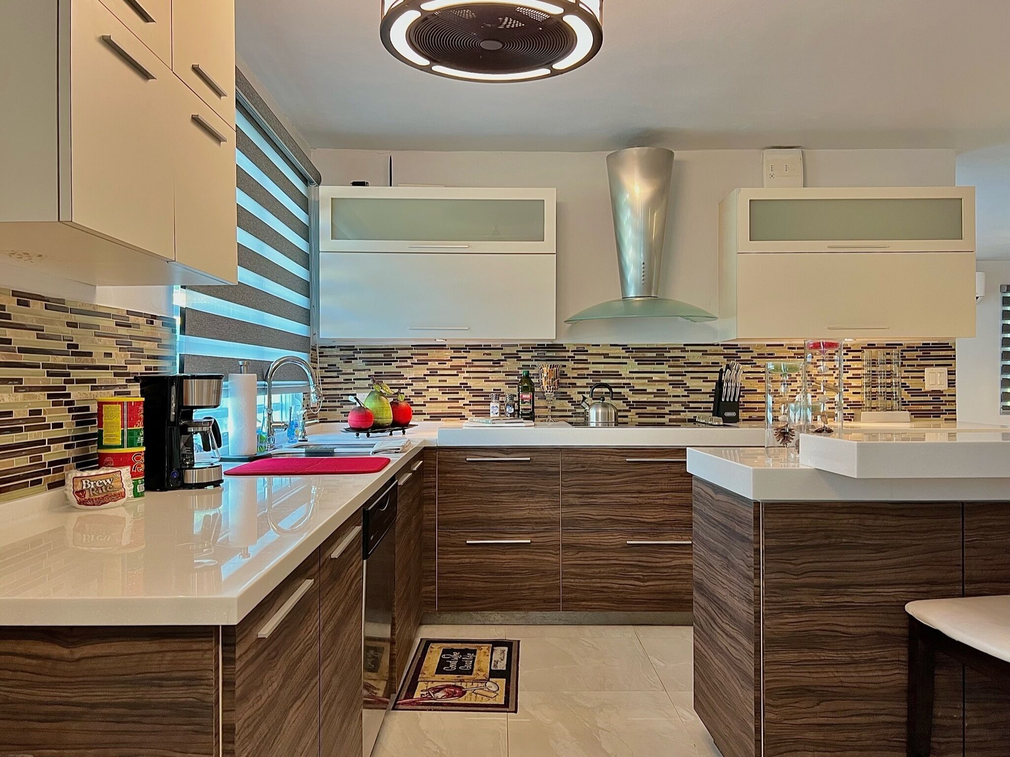 A modern kitchen with a central island, wooden cabinets, a tiled backsplash, and a built-in range hood.