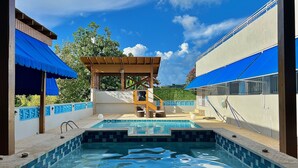 A swimming pool with a wooden deck and a covered seating area. - Luxury Villa with Pool, Heated Jacuzzi, & Terrace in El Yunque Rainforest (Río Grande)