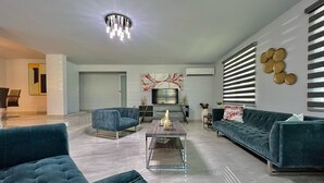 A modern living room with a chandelier, a TV, and a fireplace. - Luxury Villa with Pool, Heated Jacuzzi, & Terrace in El Yunque Rainforest (Río Grande)