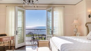 A hotel room with a balcony, a bed, a desk, and a chair. - Luxurious 6 bedroom estate with lake view & beach (Fennville)