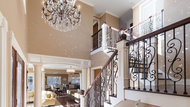 A spacious interior with a grand staircase, a chandelier, and a dining area. - Luxurious 6 bedroom estate with lake view & beach (Fennville)