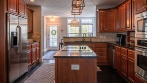 A kitchen with wooden cabinets, stainless steel appliances, and a central island. - Charming Home in Douglas - Sleeps 14 (Douglas)