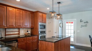 A kitchen with wooden cabinets, a central island, stainless steel appliances, and pendant lighting. - Charming Home in Douglas - Sleeps 14 (Douglas)