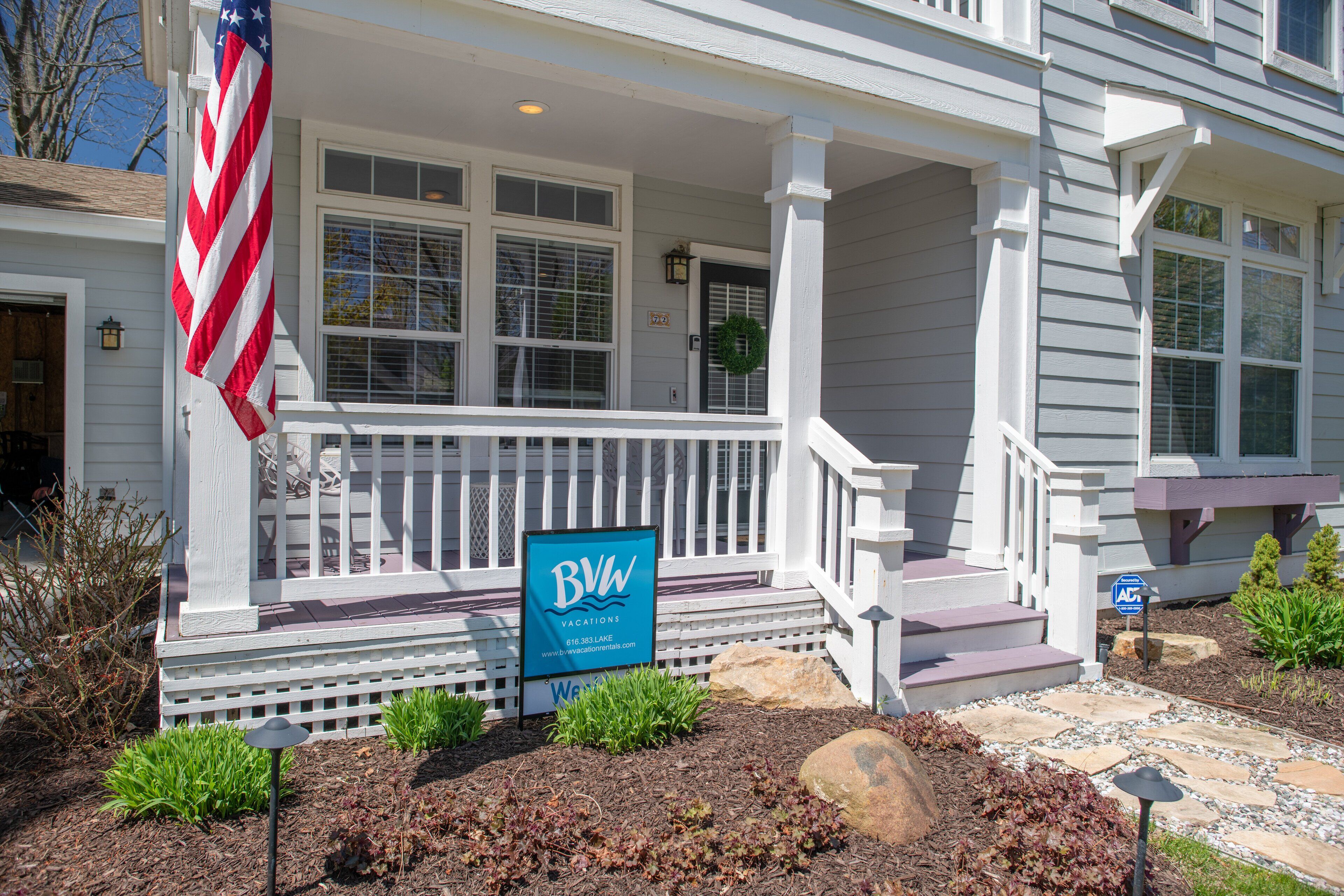 A house with a porch, a sign for B&W Vacations, and an American flag.