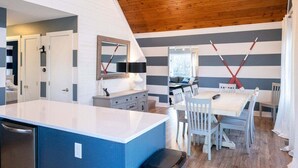 A modern kitchen with a blue island, white cabinets, and a wooden ceiling.