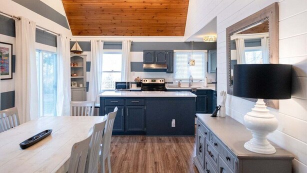 A modern kitchen with wooden ceiling, dark cabinets, and a central island.