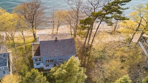 A house with a sloped roof, surrounded by trees and a beach. - Classic Lake MI Cottage w/Beach and Incredible Views (West Olive)