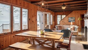 A wooden cabin with a dining area, a sofa, and a fireplace. - Classic Lake MI Cottage w/Beach and Incredible Views (West Olive)