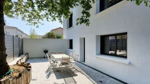 Un patio con mesa y sillas, una parrilla y una ventana con vista a un jardín.