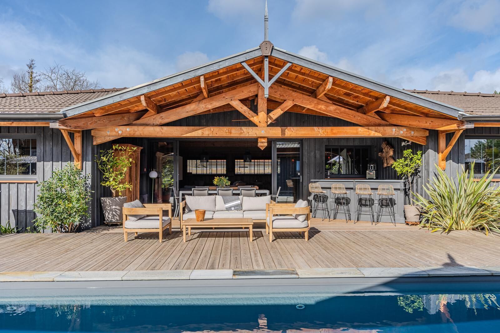 Une terrasse en bois avec des sièges d’extérieur et une piscine.