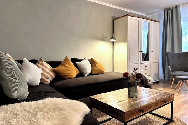 Wohnzimmer mit ausziehbarer Eckcouch. Kissen, Decken, TV.