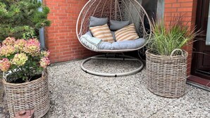 En hængekøje med puder, to fletkurve med planter, og en murstensvæg.