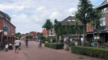 Eine Fußgängerzone mit Gebäuden, einige mit sichtbaren Schildern, und Menschen, die gehen und Fahrrad fahren.