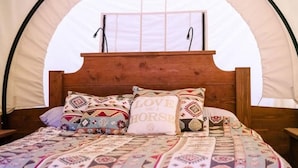 A bed with a wooden headboard, multiple patterned pillows, and a quilt.