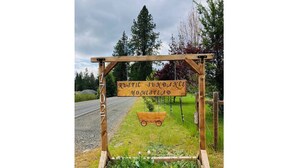 A rustic wooden sign with the text "Rustic Sundance Homestead" and a wagon wheel.