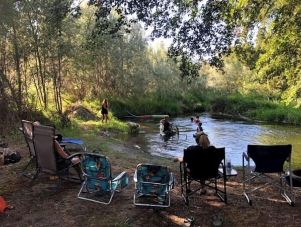 Un terrain de camping avec des chaises et une rivière.