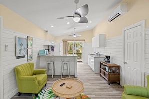 A compact kitchen with white cabinetry, a central island, and a dining area with a round table.