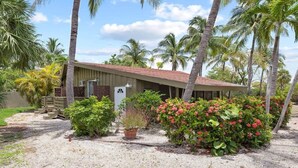 A building with a red roof, surrounded by palm trees and various plants.