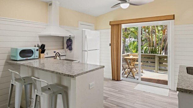 A kitchen with a microwave, refrigerator, and a ceiling fan.