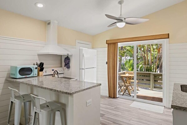 A kitchen with a microwave, refrigerator, and a ceiling fan. - The Palms Cottage One- A Green Haven on Sanibel (Sanibel)