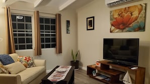 A living room with a sofa, a coffee table, a TV, and a potted plant. - Villa Rose (Charlotte Amalie)