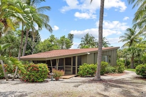 A modern building with a sloped roof, surrounded by lush greenery and palm trees.