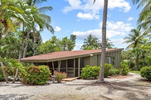 A modern building with a sloped roof, surrounded by lush greenery and palm trees.