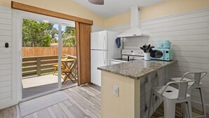 Una cocina con isla integrada, ventilador de techo y puerta corrediza de vidrio que da a un patio exterior.