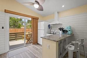A kitchen with a built-in island, a ceiling fan, and a sliding glass door leading to an outdoor patio.