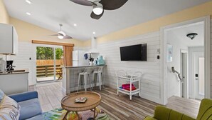 Un espacio habitable amplio con ventilador de techo, una mesa de comedor, un sofá y un televisor montado en la pared.