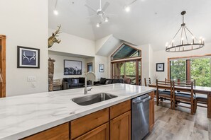 A spacious kitchen with a large island, a dining area with wooden furniture, and a living room with a fireplace.