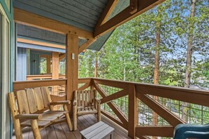Une terrasse en bois avec un banc et une table, donnant sur une forêt.