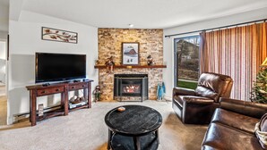 A living room with a fireplace, leather sofa, and a flat-screen TV.