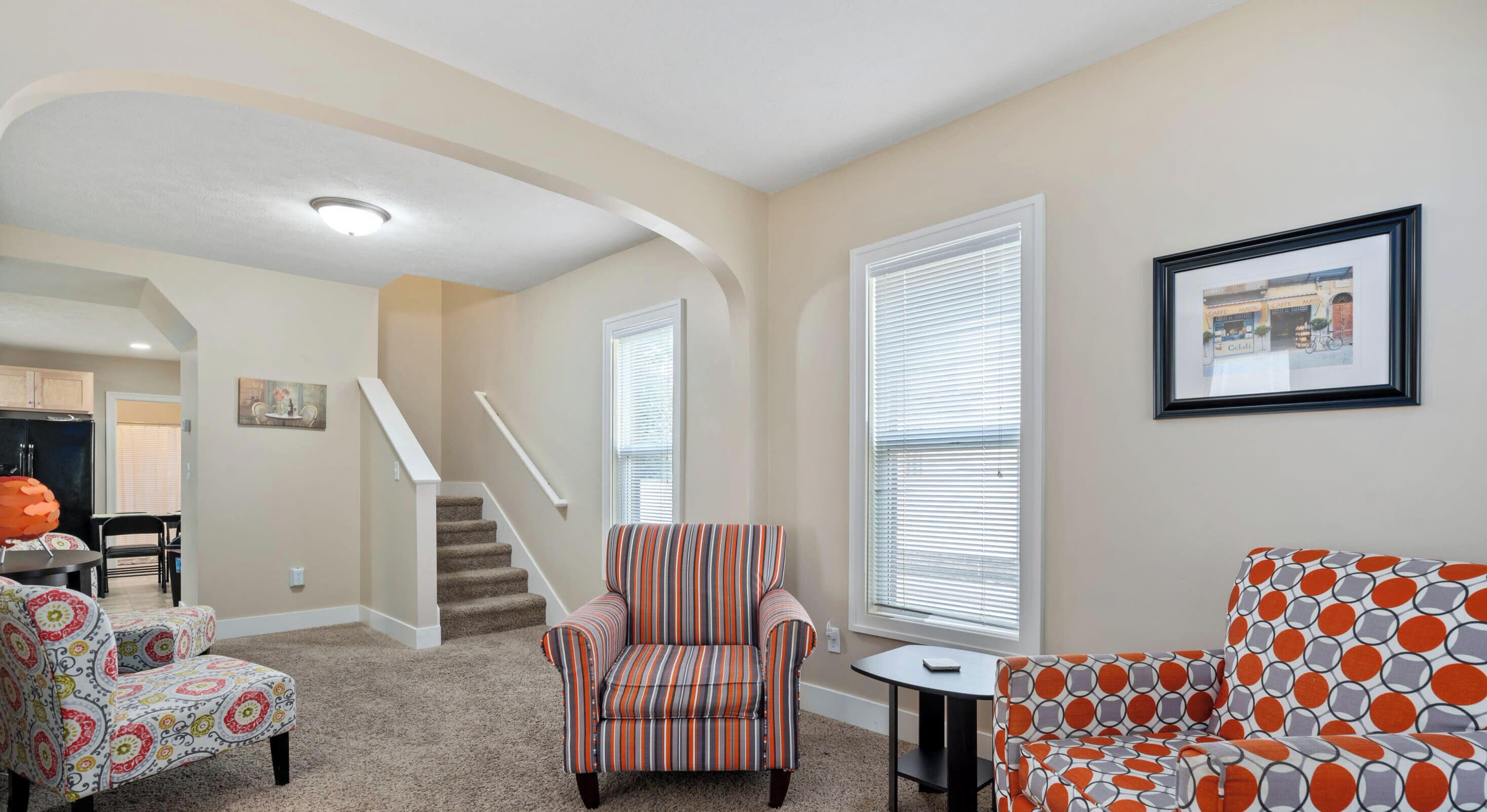 A living room with a striped armchair, a patterned sofa, and a small table.