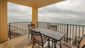 A balcony with a table and chairs overlooking a beach.