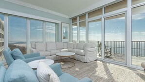 A spacious balcony with a white sectional sofa, a round coffee table, and a view of the ocean. - 🌊☀Phoenix Orange Beach II 1005 - Beautiful 4BR Condo!☀🌊 (Orange Beach)