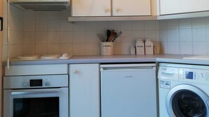 Een compacte keuken met witte kastjes, een Bosch oven, een vaatwasser en een wasmachine.