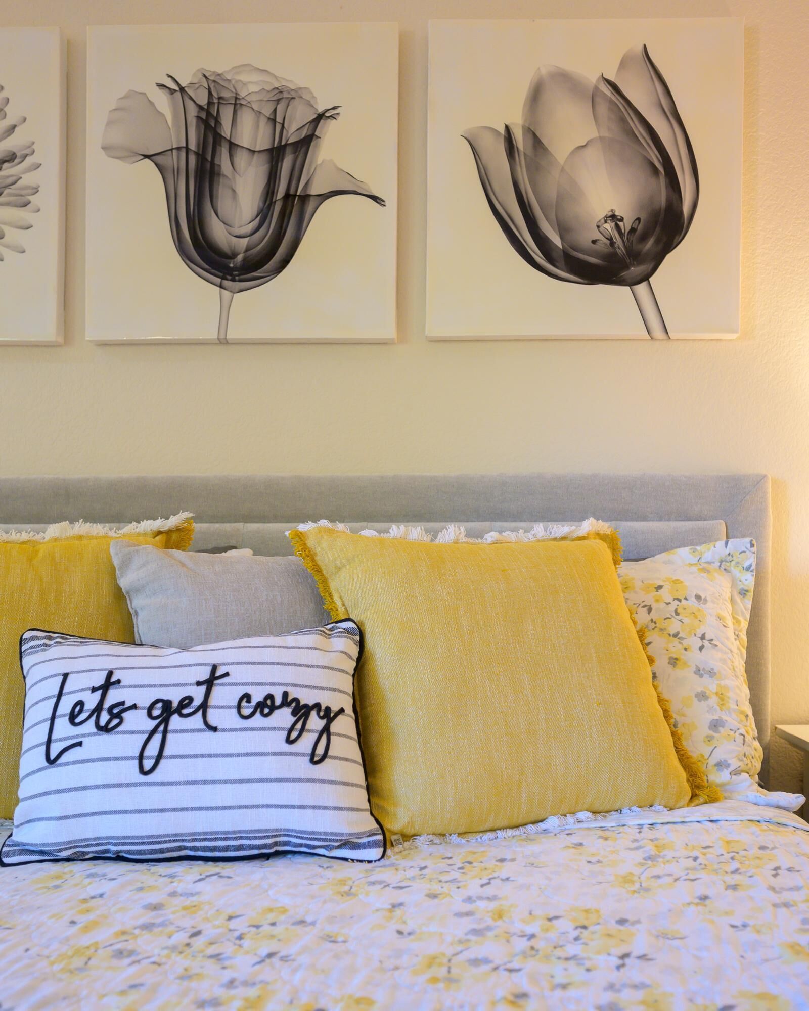 Ein Schlafzimmer mit einem Bett, gelben Kissen und einem Kissen mit dem Aufdruck 'let's get cozy'.