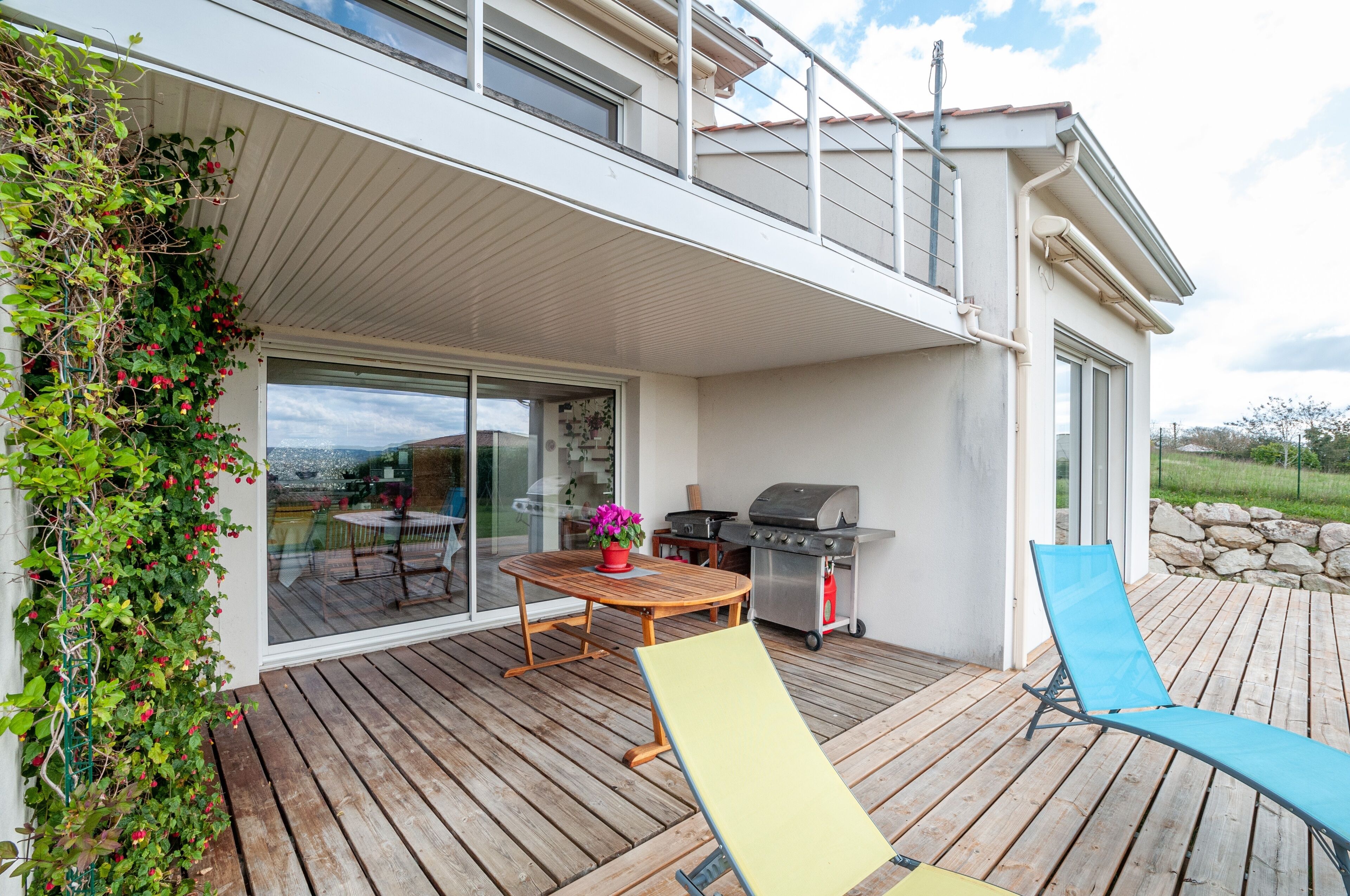 Een terras met een tafel, stoelen, een barbecue en een ligstoel.